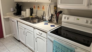 A kitchen with white cabinets, a double sink, a microwave, and a stove. - Charming 2-bedroom house with WiFi, AC in beautiful Gulf Breeze (Gulf Breeze)
