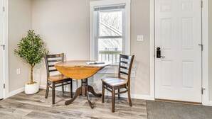 Un coin repas avec une table et des chaises en bois, une plante en pot et une porte blanche.