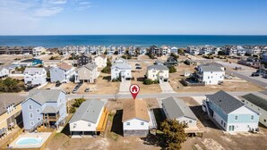 An aerial view of a coastal residential area with houses, a swimming pool, and a clear view of the ocean. - Pool/Hot tub -Fenced yard -1 dog friendly (Nags Head)