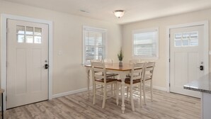 A dining area with a wooden table and chairs, white walls, and a ceiling light. - Pool/Hot tub -Fenced yard -1 dog friendly (Nags Head)