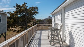 A wooden deck with a railing, a chair, and a table. - Pool/Hot tub -Fenced yard -1 dog friendly (Nags Head)