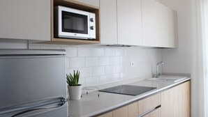 A modern kitchen with white cabinets, a built-in microwave, a stainless steel refrigerator, a sink, and a potted plant. - Dainese Apartments, Casa Miriam (Jesolo)