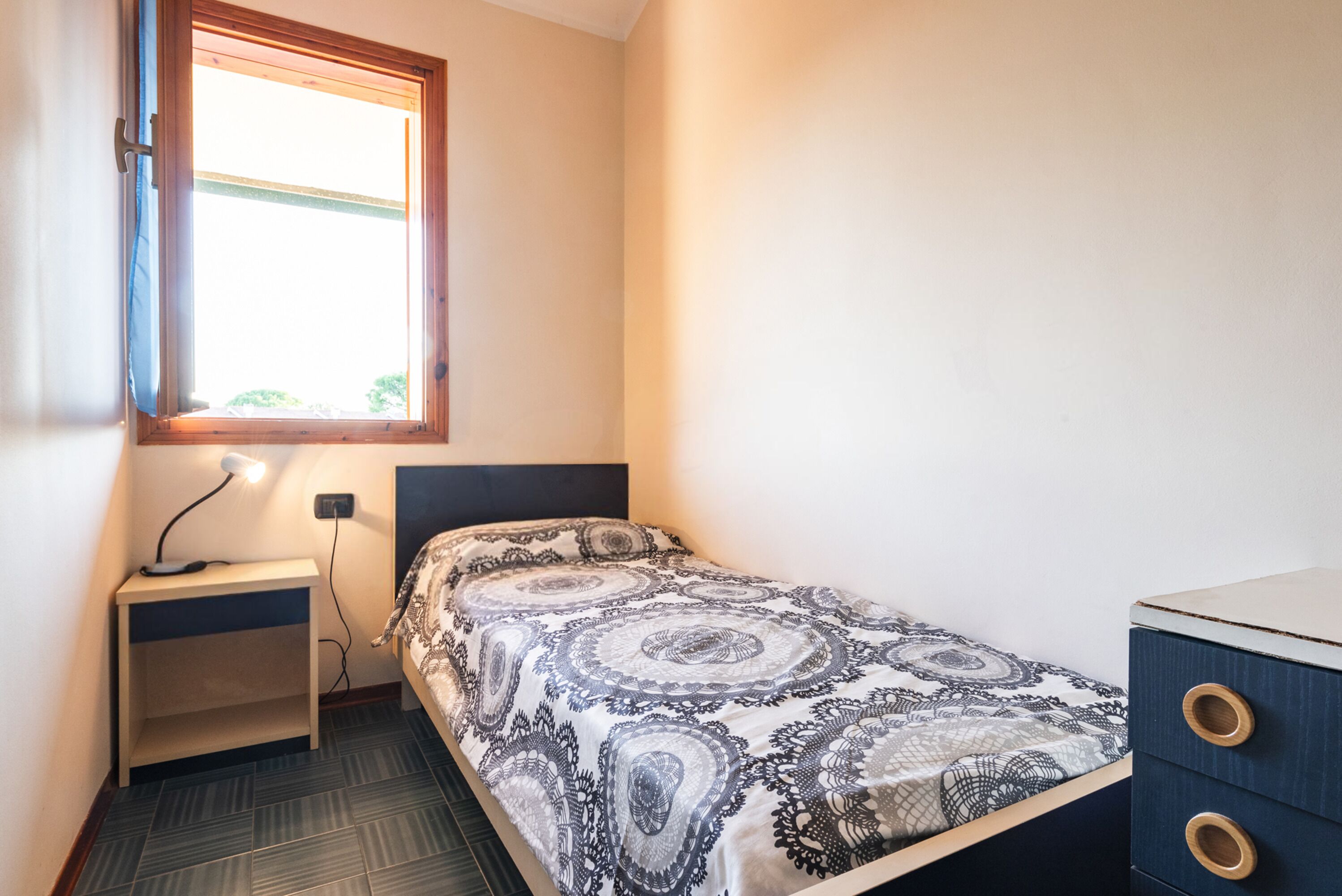 Une petite chambre à coucher comprenant un lit, une table de chevet, un bureau et une commode.