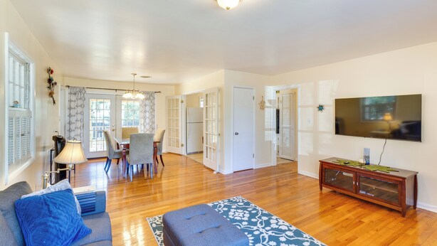 A spacious living room with hardwood floors, a grey sofa, a blue ottoman, and a flat-screen TV mounted on the wall. - 4 Mi to FSU! Family Gem w/ Deck in Tallahassee (Tallahassee)