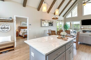A spacious kitchen with a marble countertop, wooden ceiling beams, and pendant lighting. - Luxury Cabin, Mountain Views, Hot Tub, EV Charger (Ellijay)