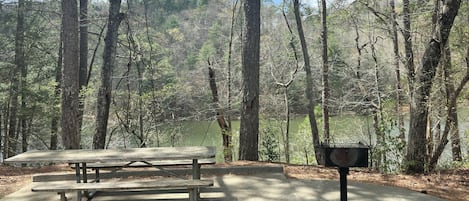 Una mesa de picnic en un área boscosa con un buzón.