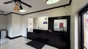 A hotel reception area with a black reception desk, a clock, and a sign for the Executive Inn. - Executive Inn & Suites (Pittsburg)