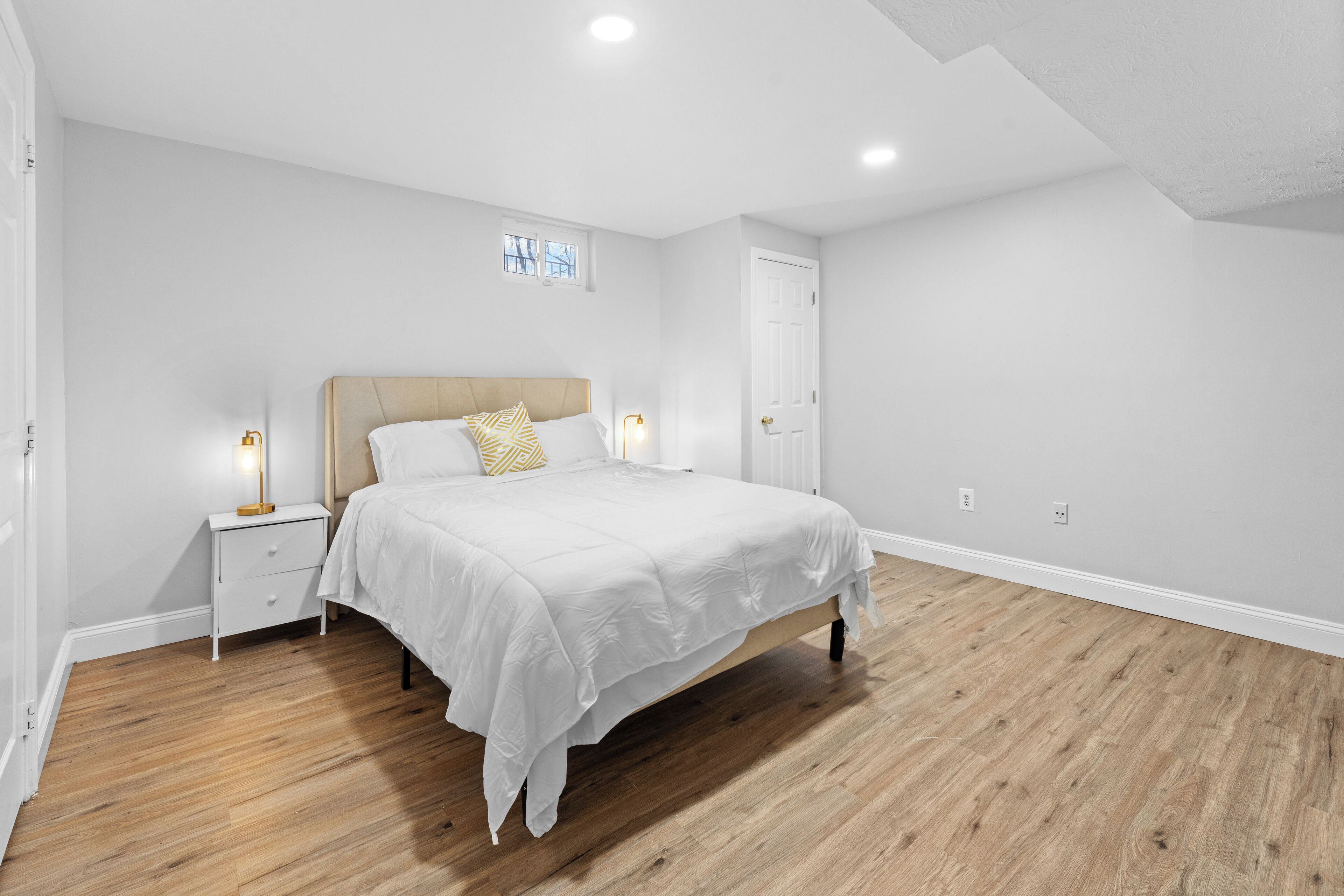 A bedroom with a bed, nightstands, and a window.