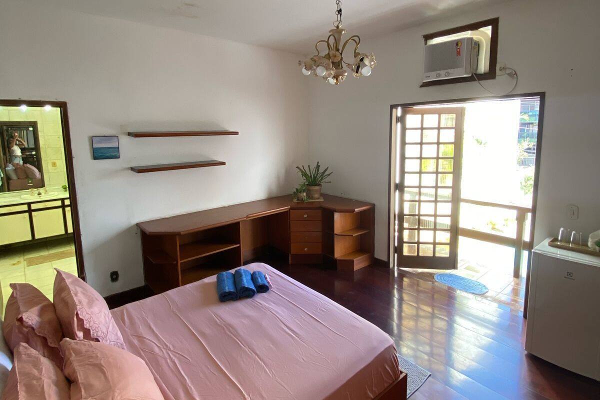 A bedroom with a large bed, wooden desk, and a ceiling fan.