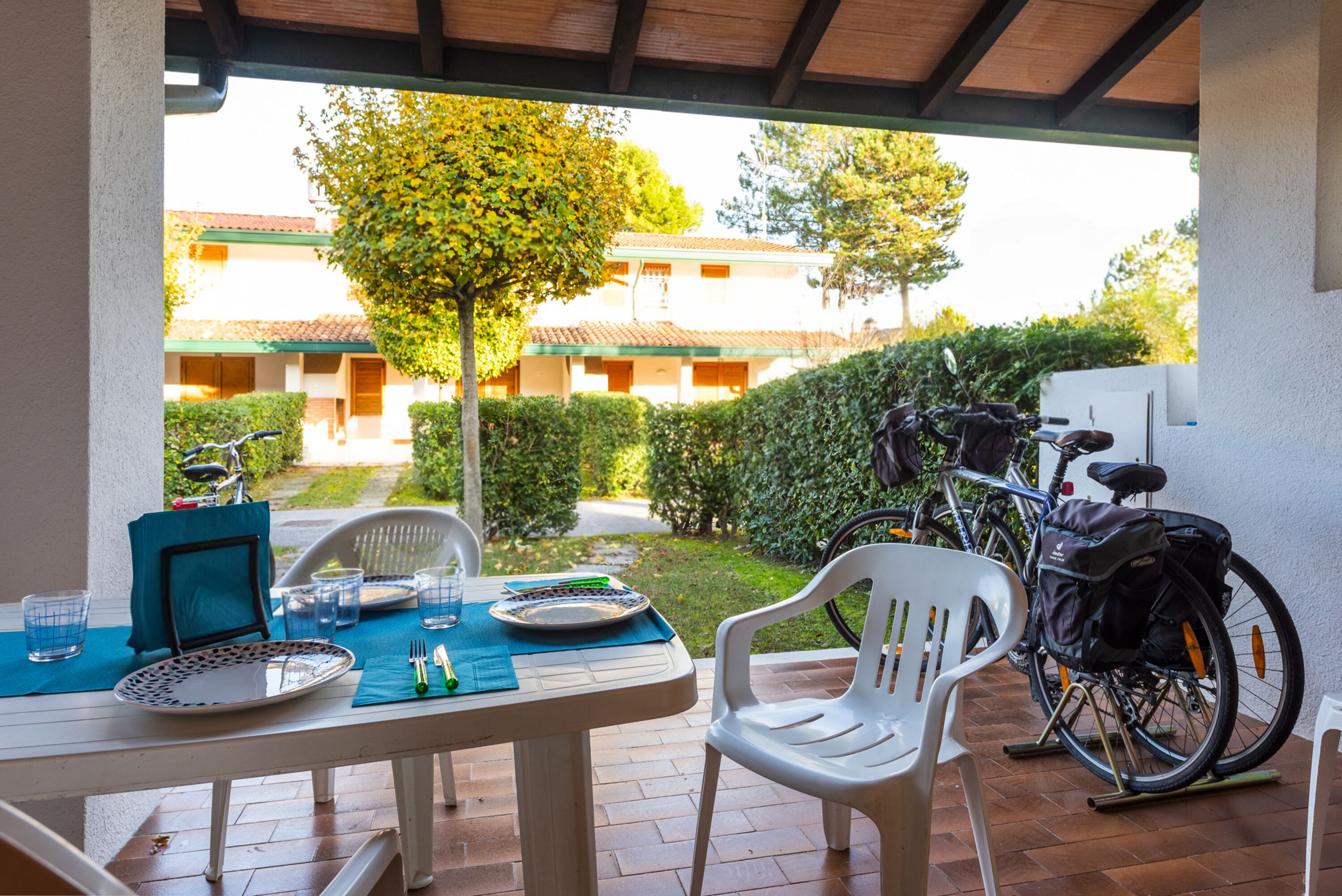 An outdoor patio with a table set for two, a bicycle, and a chair.