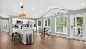 Una cocina moderna con armarios blancos, una isla central y un comedor con mesa y sillas.