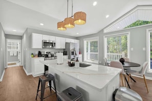 Una cocina moderna con armarios blancos, una isla central y un comedor con mesa y sillas.