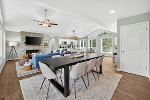 A modern open-plan living space with a dining area, kitchen, and a fireplace.