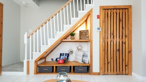 Una escalera con barandilla de madera y una puerta de madera con listones verticales.