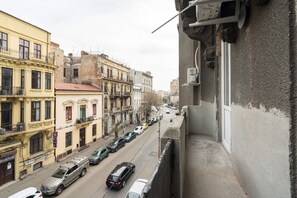 A street view with buildings, cars, and a balcony.