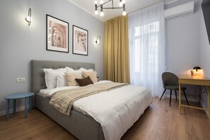 A modern bedroom with a bed, a desk, a chair, and two wall-mounted light fixtures.