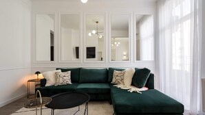 A modern living room with a green sectional sofa, a round coffee table, and a large mirror above the sofa. - Elegant & Bright 2BR Condos - Steps from Old Town (Bucharest)