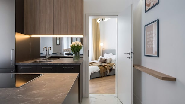 A modern kitchen with a marble countertop, wooden cabinets, and a built-in sink. - Elegant & Bright 2BR Condos - Steps from Old Town (Bucharest)