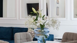 A dining area with a round table, four chairs, and a vase with flowers. - Elegant & Bright 2BR Condos - Steps from Old Town (Bucharest)