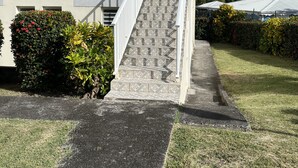 A two-story building with a yellow facade, a white staircase, and a small balcony. - Alamanda pink (Sainte-Anne)