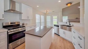 A modern kitchen with stainless steel appliances, white cabinetry, and a central island.