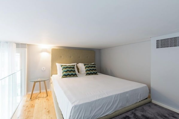 Une chambre à coucher avec un lit, une table de chevet, une lampe et une fenêtre.