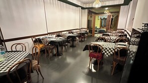 Ein Restaurant mit modernem Ambiente, das sich durch karierte Tischdecken, Korbstühle und Pendelleuchten auszeichnet.