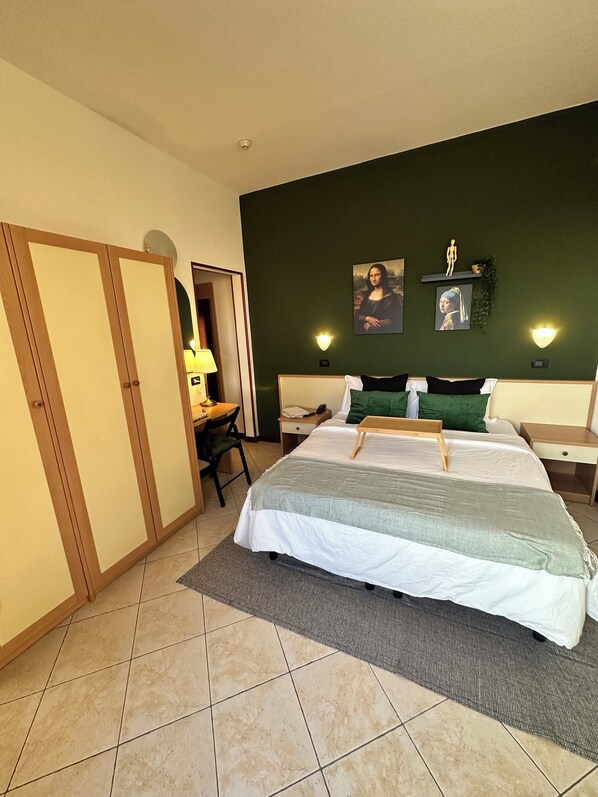 Un dormitorio con cama, mesitas de noche, escritorio y silla.