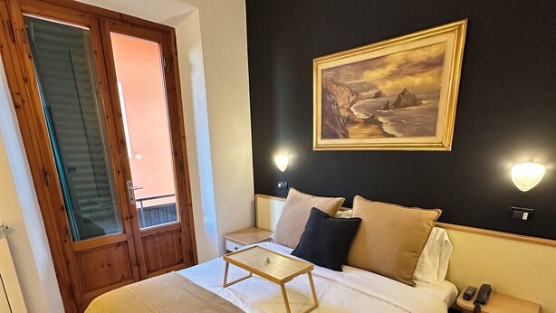 Ein Hotelzimmer mit Bett, Nachttisch, Lampe und einem Bild an der Wand.