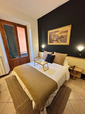 Una habitación de hotel con cama, mesita de noche, lámpara y un cuadro en la pared.