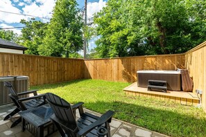 Un jardin avec une clôture en bois, un jacuzzi et du mobilier d’extérieur.