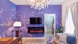 Un salon avec une cheminée, un téléviseur et un lustre.