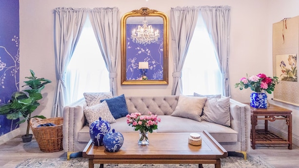 Une pièce comprenant un canapé, une table basse, un lustre et un tableau accroché au mur.