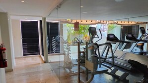 Een sportschool met trainingsapparatuur, een brandblusser en een glazen wand.