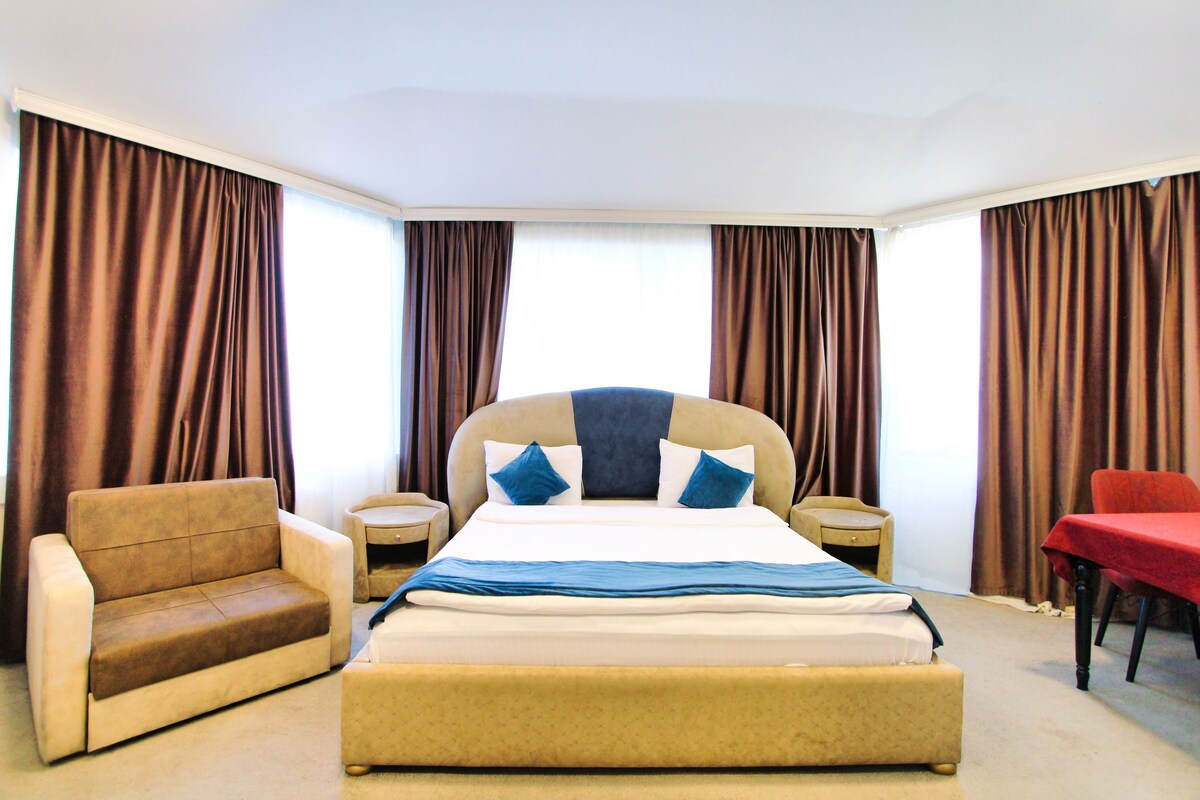 A hotel room with a bed, a sofa, a chair, and a desk.