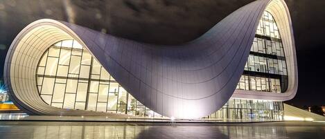 A modern architectural building with a curved design, large windows, and a reflective floor.