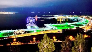 Un paseo marítimo con noria, un puente y un puerto deportivo.