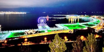 Een waterkantpromenade met een reuzenrad, een brug en een jachthaven.
