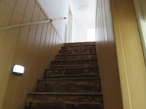Una escalera de madera con barandilla y un interruptor de luz en la pared.