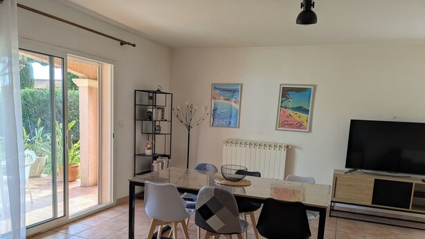 A dining area with a table, chairs, a bookshelf, and a TV. - Quiet, spacious house, close to the station and amenities, 2 km from the beach (Saint-Cyr-sur-Mer)