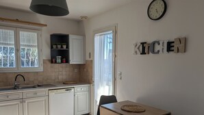A modern kitchen with white cabinets, a dishwasher, and a wooden table with a placemat. - Quiet, spacious house, close to the station and amenities, 2 km from the beach (Saint-Cyr-sur-Mer)