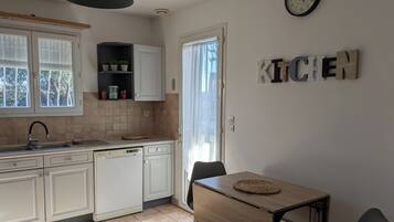 Une cuisine moderne avec des meubles blancs, un lave-vaisselle et une table en bois sur laquelle est posée une nappe.