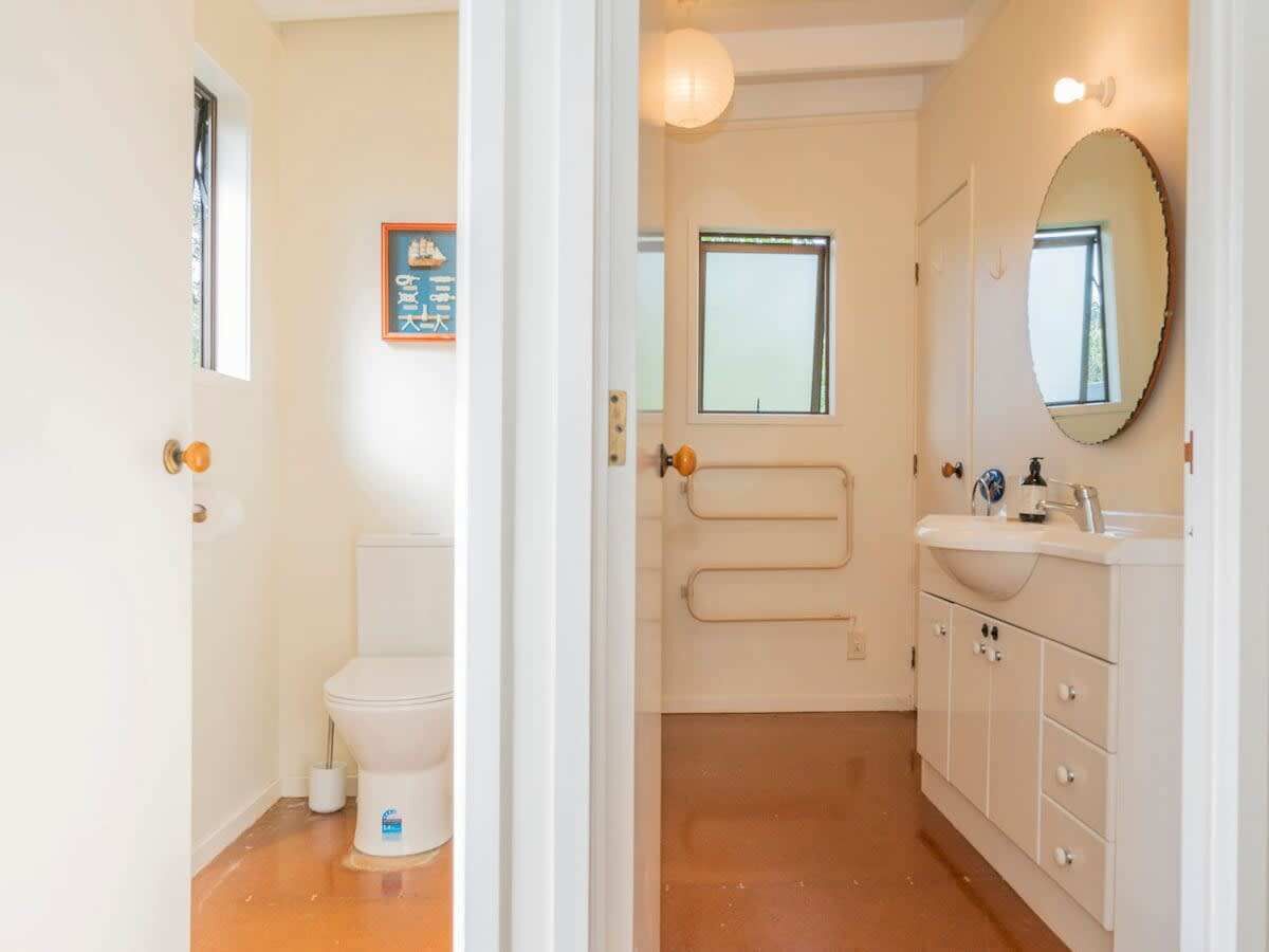 A bathroom with a toilet, a shower, a sink, and a mirror.