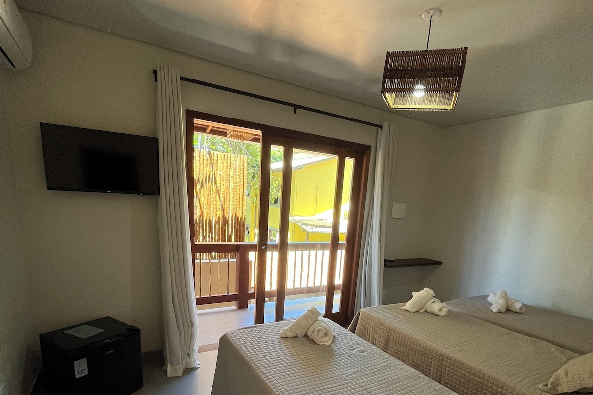 A hotel room with two beds, a TV, a suitcase, and a balcony with curtains.