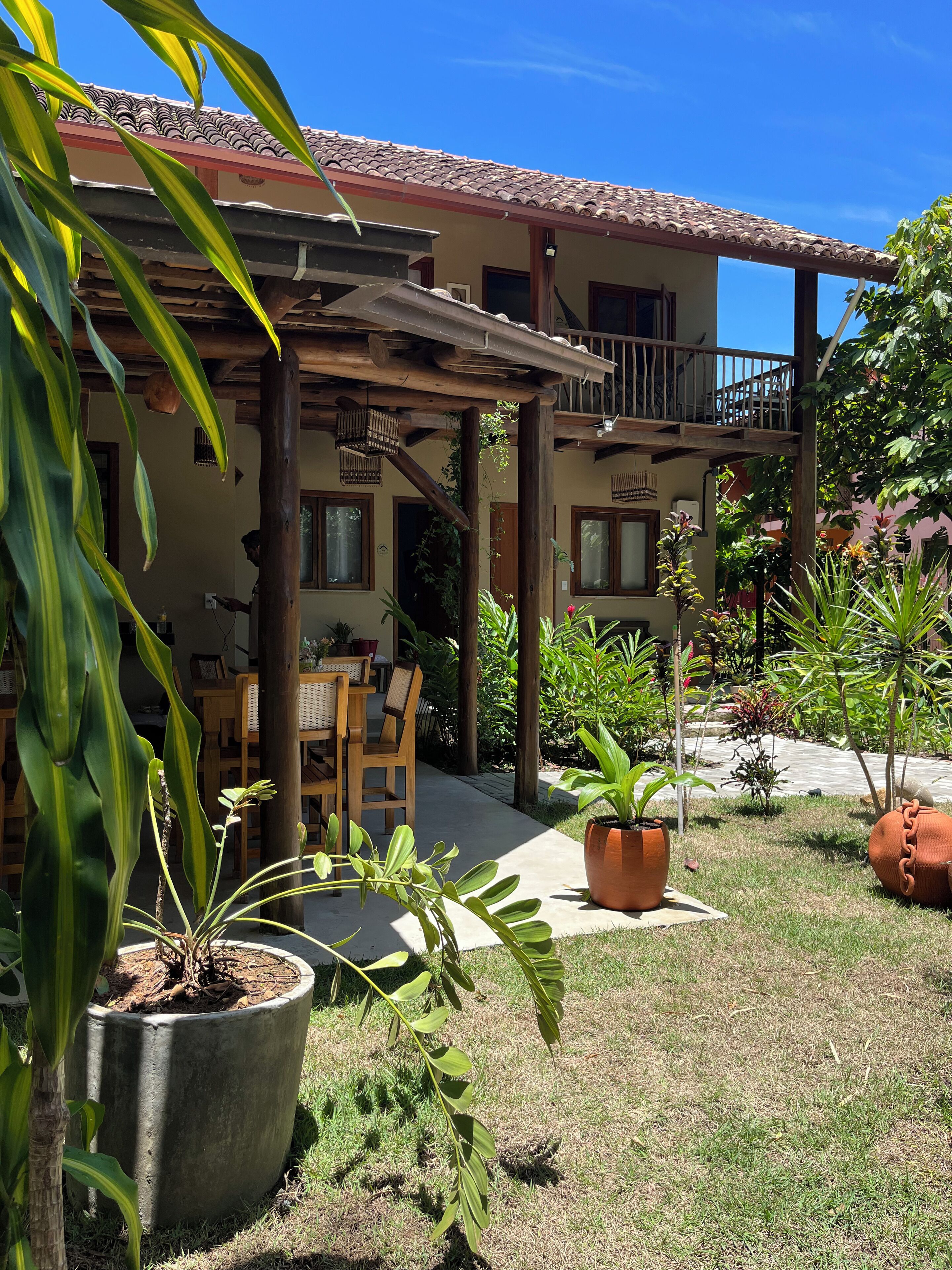 Ein Innenhof mit einer Holzpergola, Blumentöpfen und einer Sitzecke mit Tisch und Stühlen.