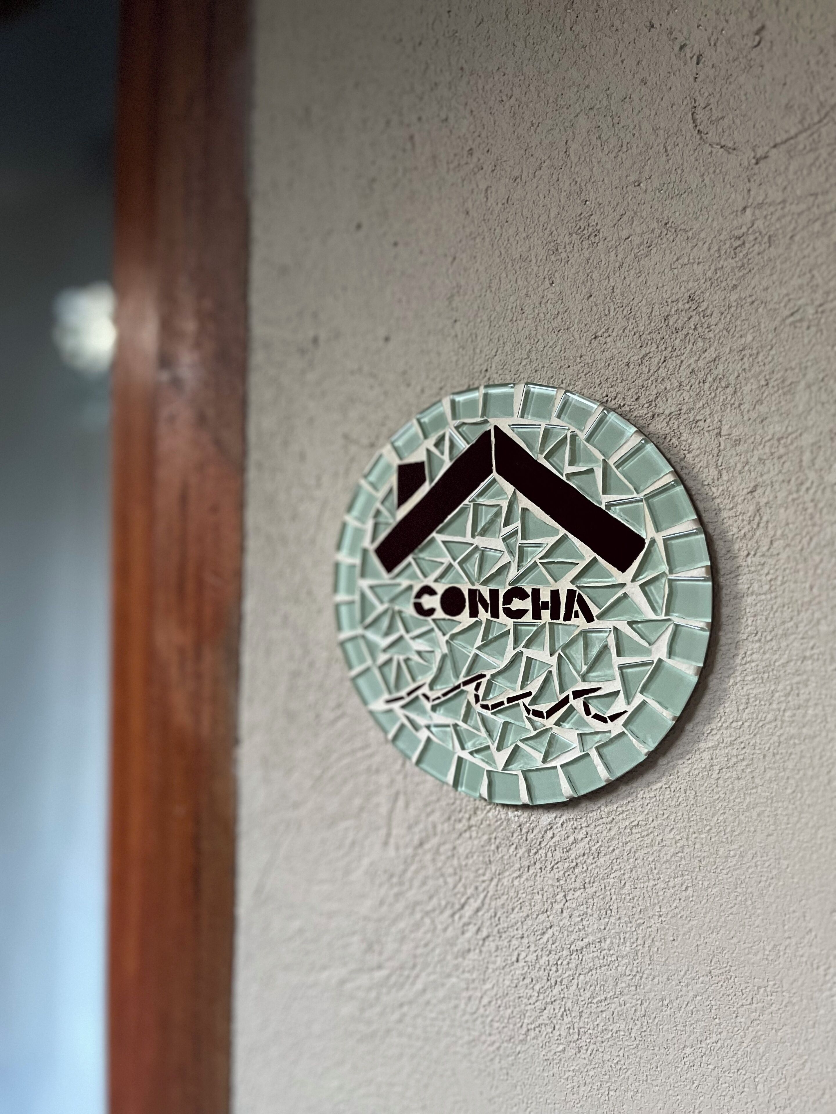 A circular mosaic with the word "CONCHA" and some text in another language.