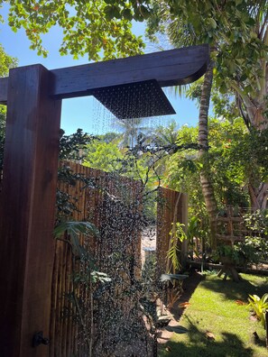 A wooden pergola with a water feature, surrounded by lush greenery and a wooden fence. - Pousada Vilarejo (Itacaré)