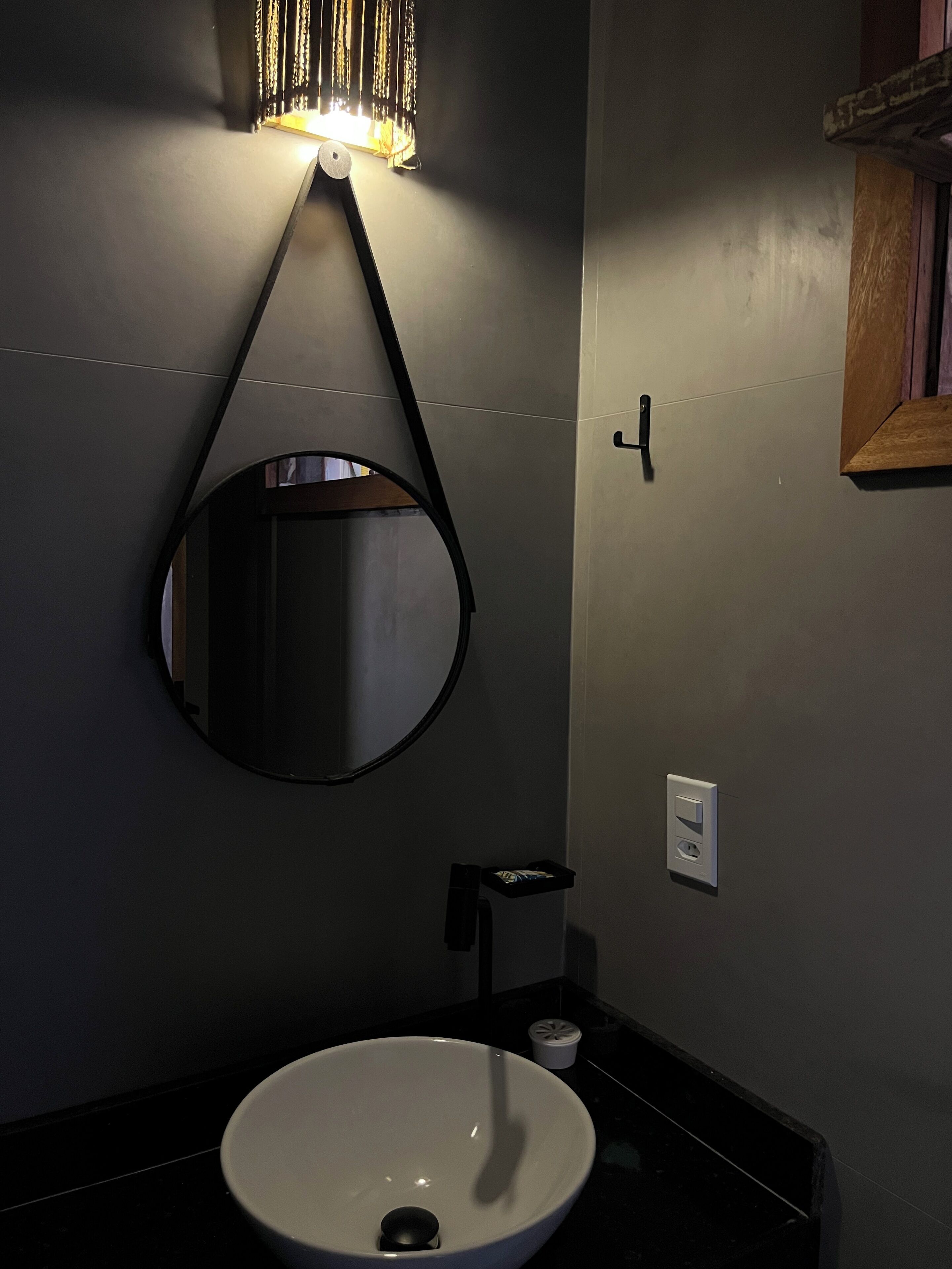 A bathroom with a round mirror, a sink, and a wall-mounted light fixture.