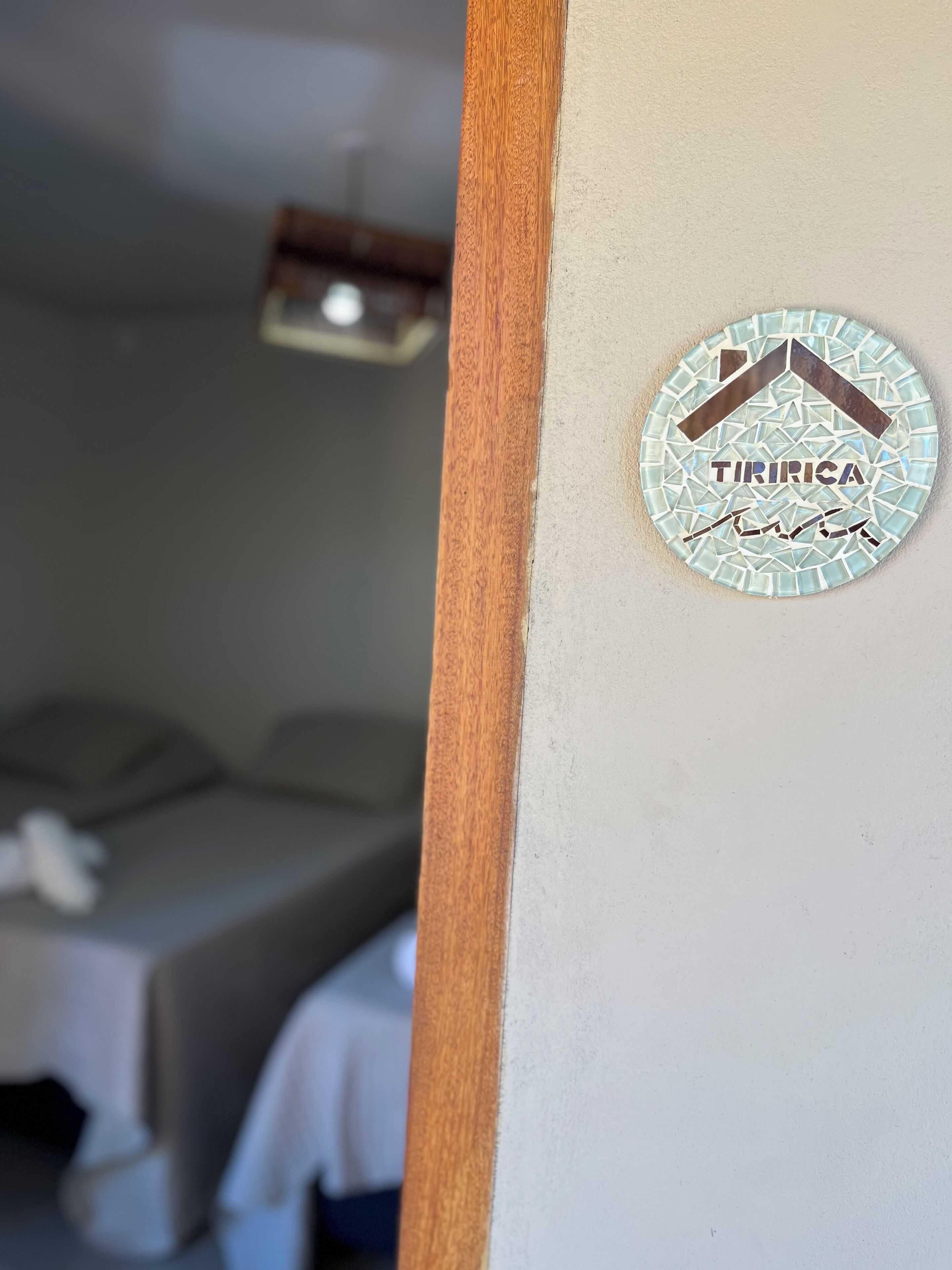 Ein Zimmer mit einem Bett und einem an der Wand befestigten Schild mit der Aufschrift 'TIRIRICA'.