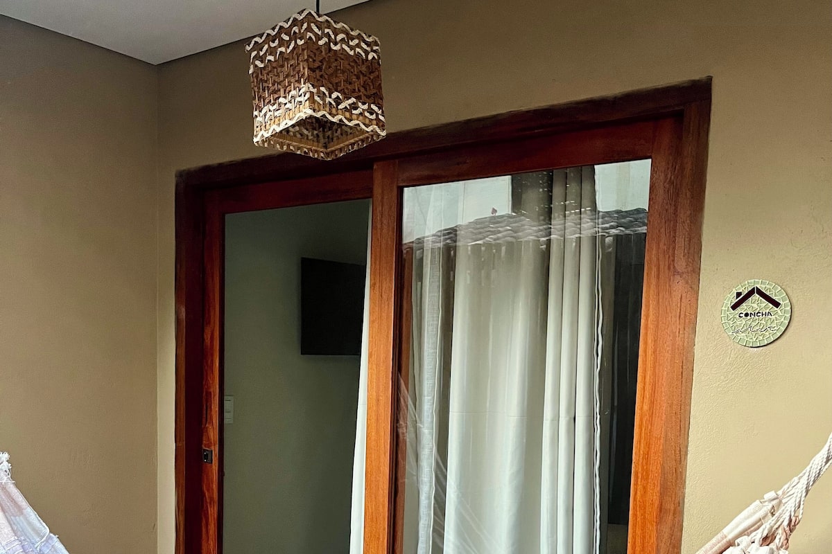 A room with a hammock tied to a wooden door frame, a ceiling light fixture, and a wall-mounted sign.